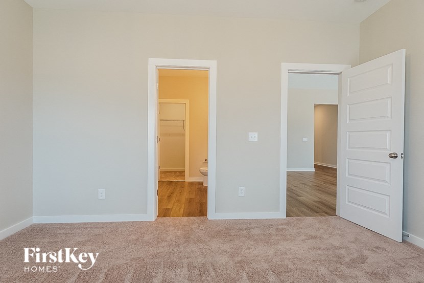 a bedroom with an open door and a hallway to a bathroom