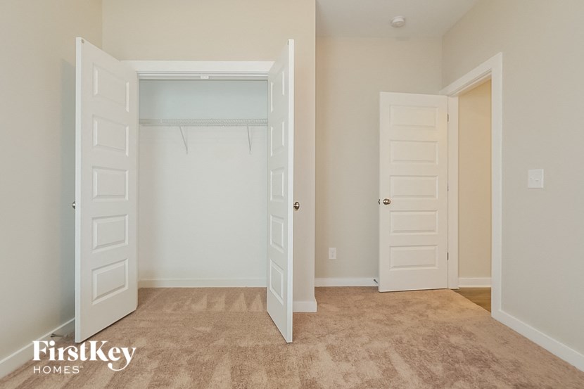 an empty bedroom with an open closet and two doors