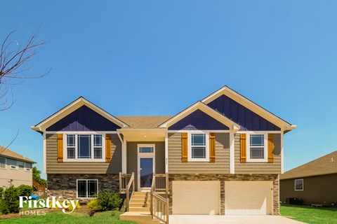 a tan house with yellow trim and a blue sky