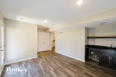 a living room and kitchen with wood flooring and white walls