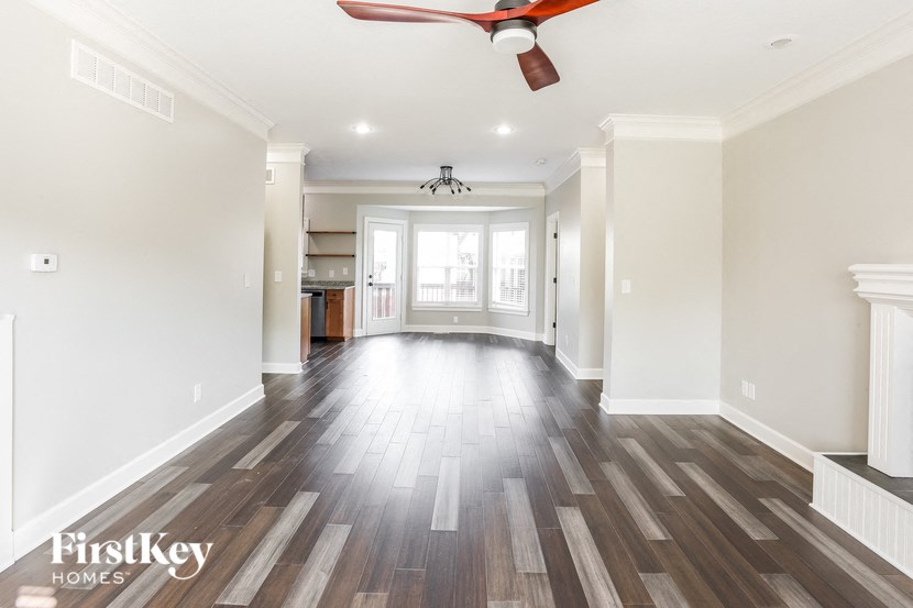 A spacious room with wooden flooring and a ceiling fan.