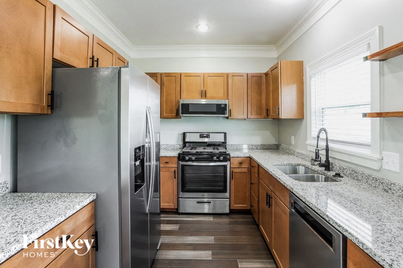 A kitchen with a refrigerator, oven, microwave, and sink.