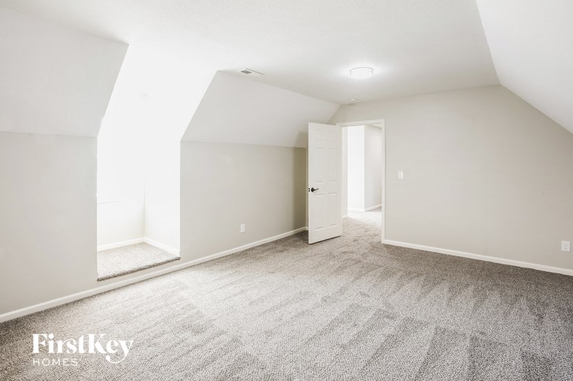 A spacious room with a carpeted floor and a doorway leading to another room.