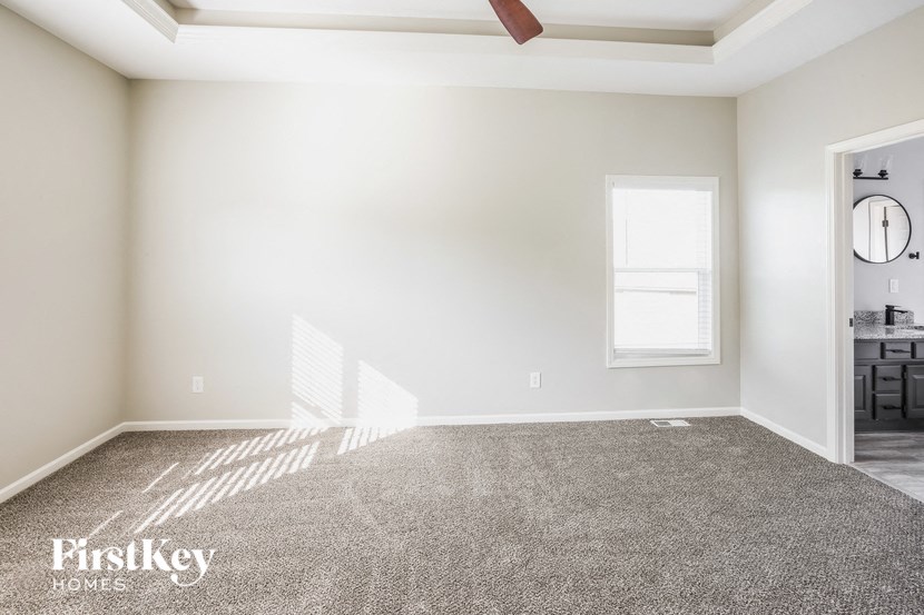 A room with a carpeted floor and a ceiling fan.