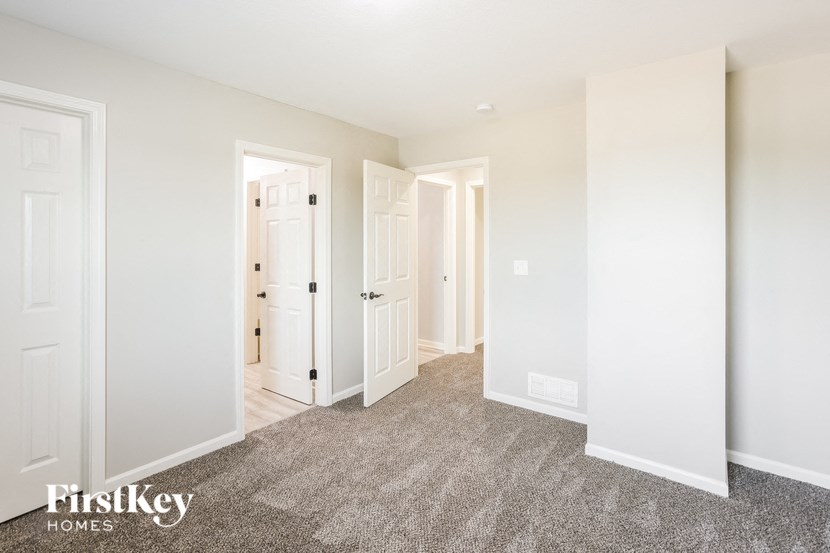 A carpeted room with three doors and a wall-mounted light fixture.