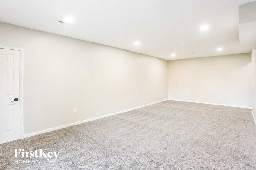 A spacious room with a carpeted floor and a door on the left side.