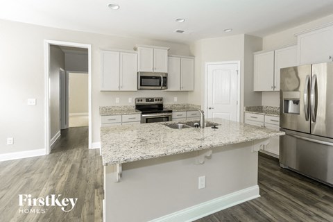 a kitchen with white cabinets and a marble counter top