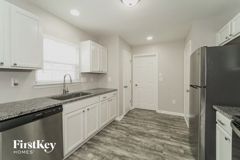 A kitchen with a black fridge and a sink with a black dishwasher.