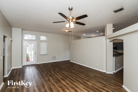 an empty living room with a ceiling fan