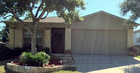 a tan house with a tree and a driveway