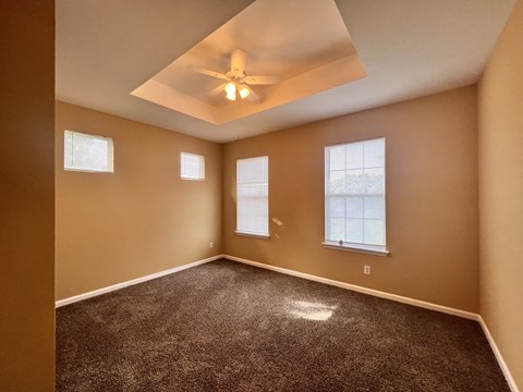 A room with a carpeted floor and a ceiling fan.