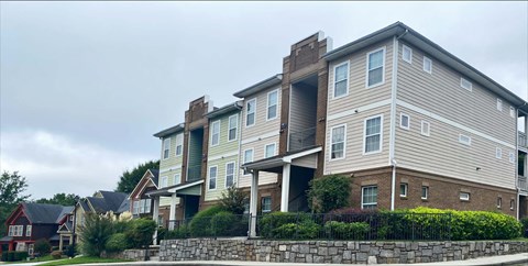 A large apartment building with a stone wall in front.
