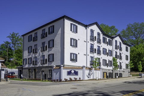 a large white building on a street corner with trees