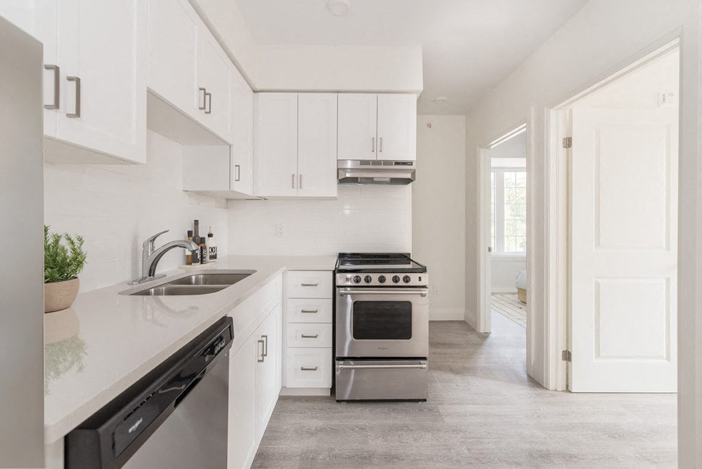a white kitchen with stainless steel appliances and white cabinets