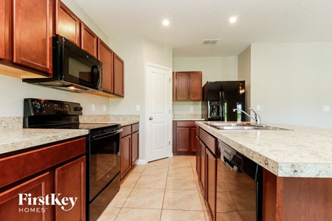 a kitchen with wood cabinets and marble counter tops and black appliances