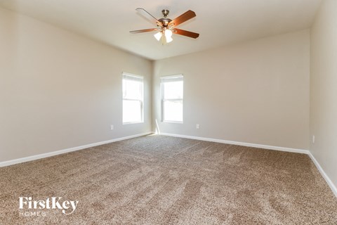 the spacious living room with ceiling fan and carpet