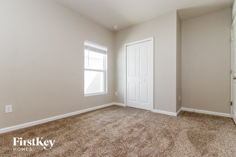 a bedroom with carpet and a white door and window