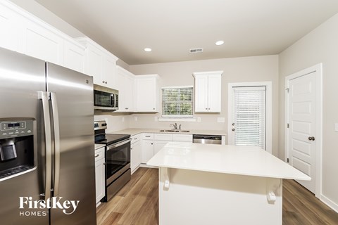 A modern kitchen with a stainless steel refrigerator and white cabinets.