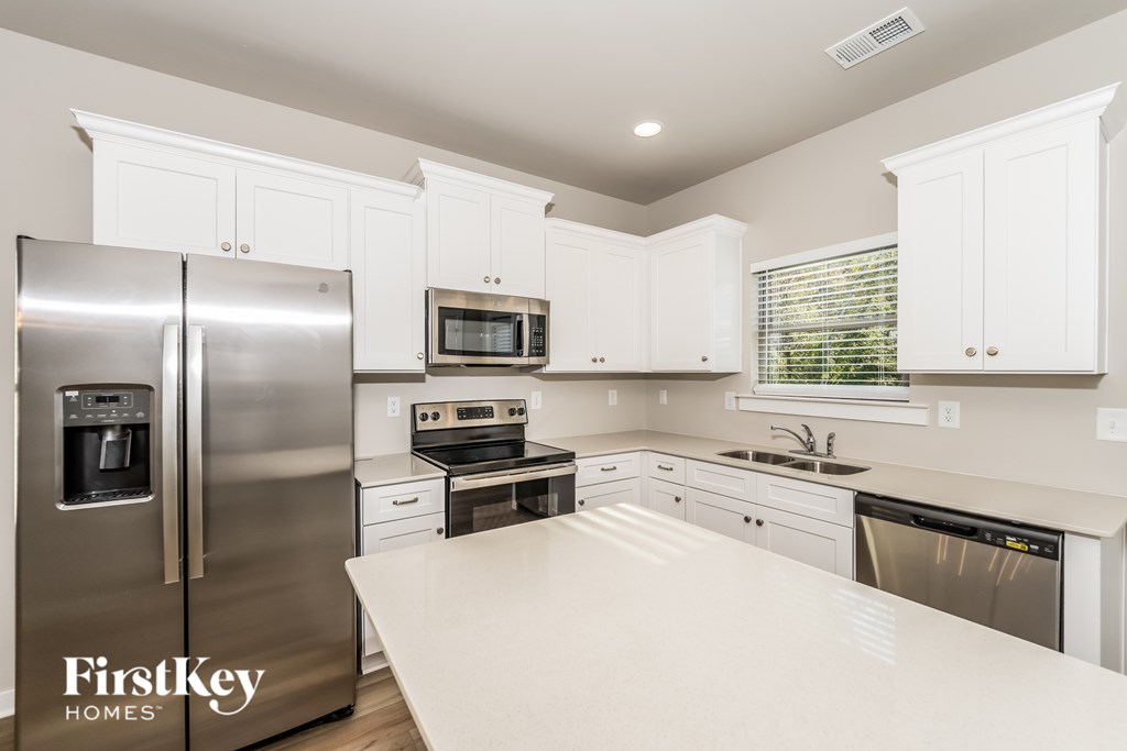 A kitchen with a refrigerator, microwave, oven, sink, and dishwasher.