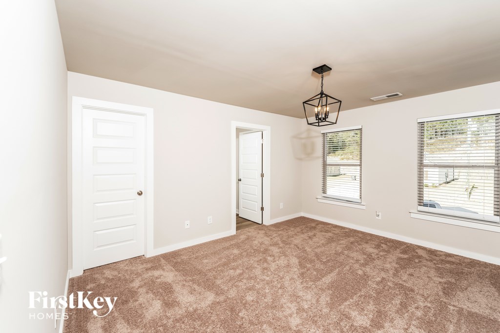 A room with a carpeted floor and a chandelier hanging from the ceiling.