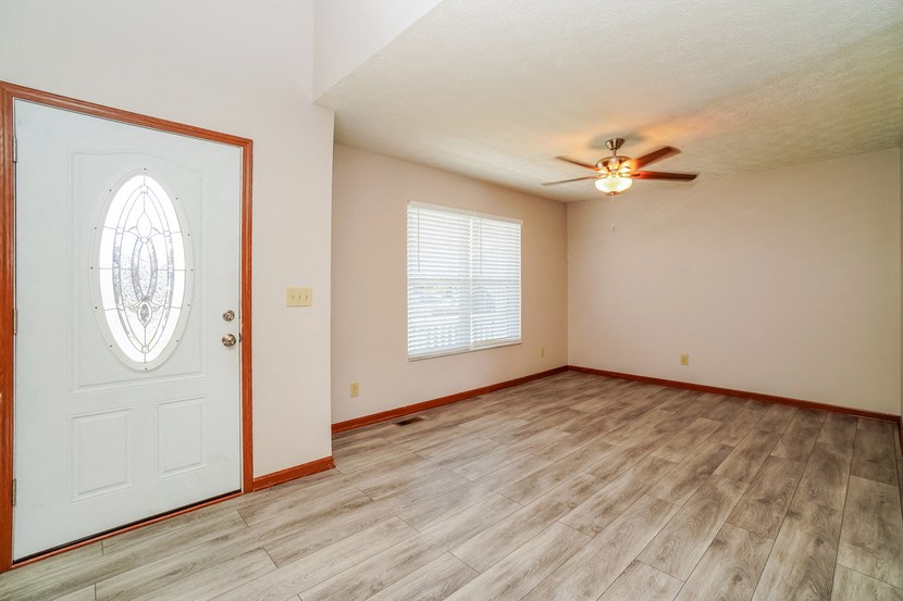A room with a ceiling fan and a door with a stained glass window.