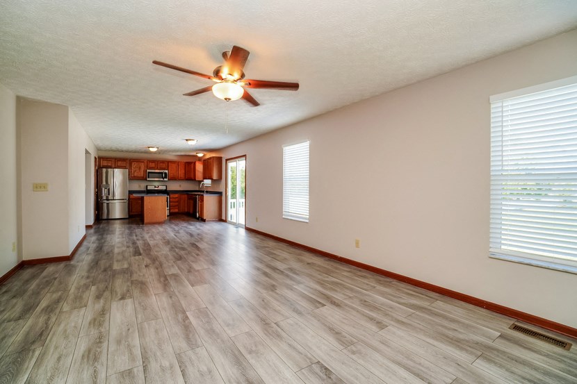 A room with a ceiling fan and wooden flooring.