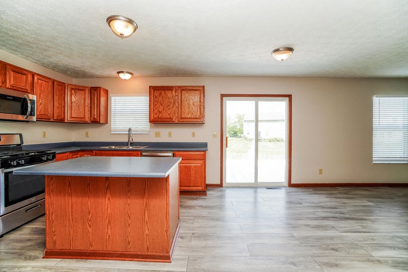 A kitchen with wooden cabinets and a large island.