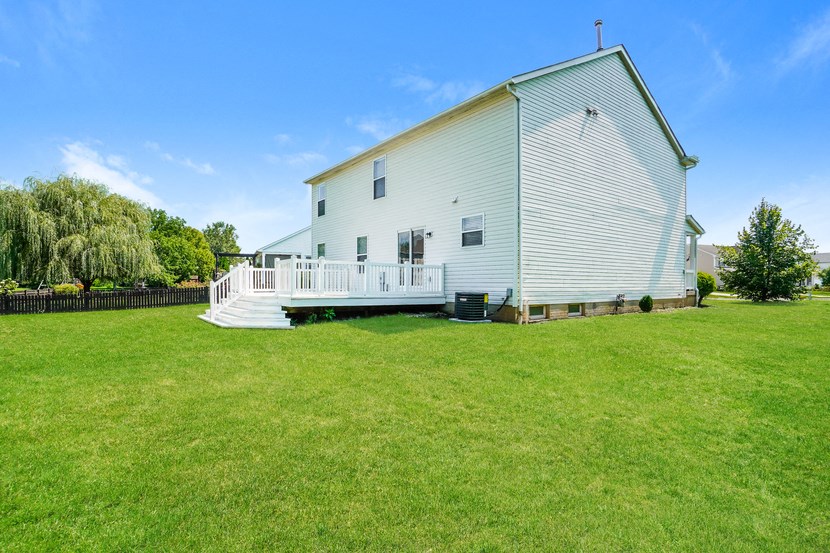 A white barn with a yellow roof stands in a grassy field.