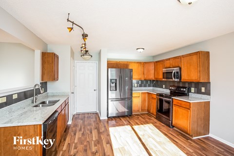 A kitchen with wooden cabinets and a black fridge.
