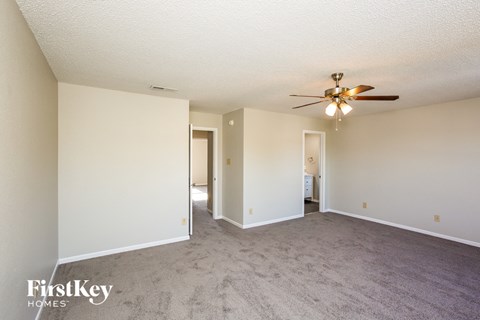 A spacious room with a ceiling fan and carpeted floor.