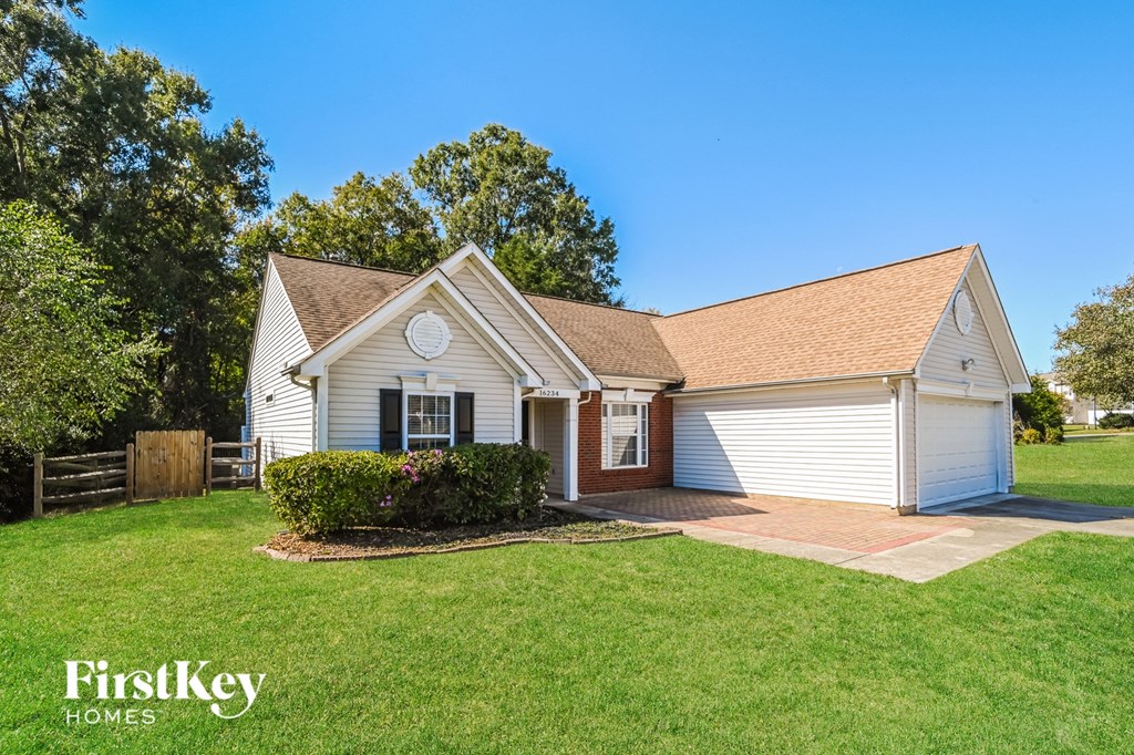 a small white house with a lawn and a driveway