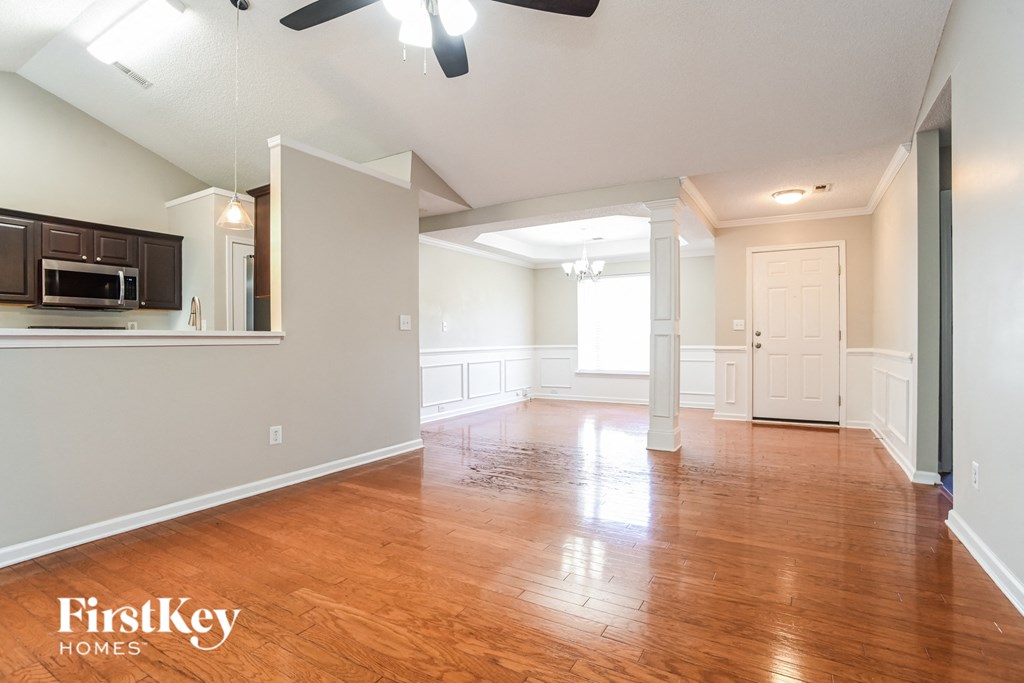 an empty living room with wood floors and a kitchen