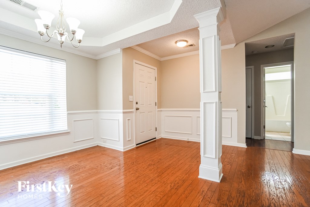 an empty living room with wood floors and white pillars
