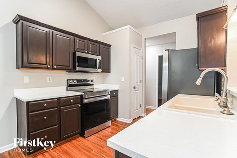 a kitchen with dark wood cabinets and white countertops and a sink and a microwave