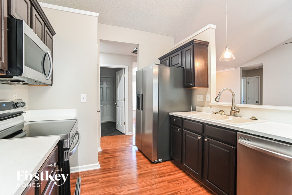 a kitchen with black cabinets and stainless steel appliances and white counter tops