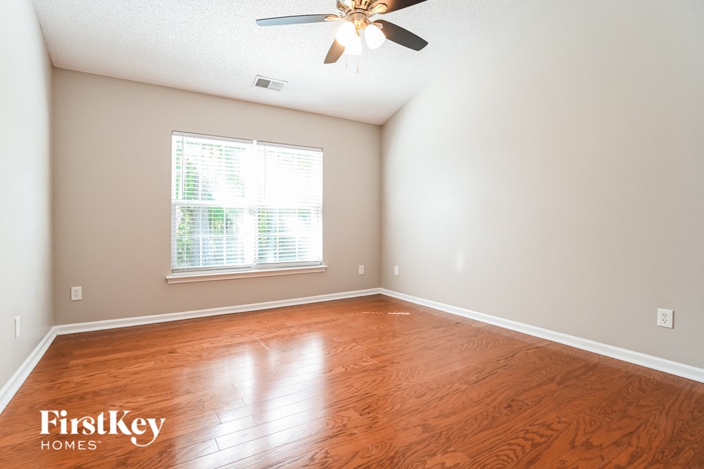a empty room with wood floors and a ceiling fan