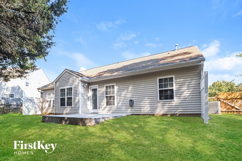 a small white house with a grassy yard and a fence