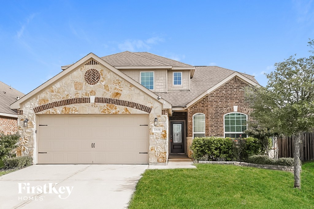 A house with a garage and a driveway in front of it.