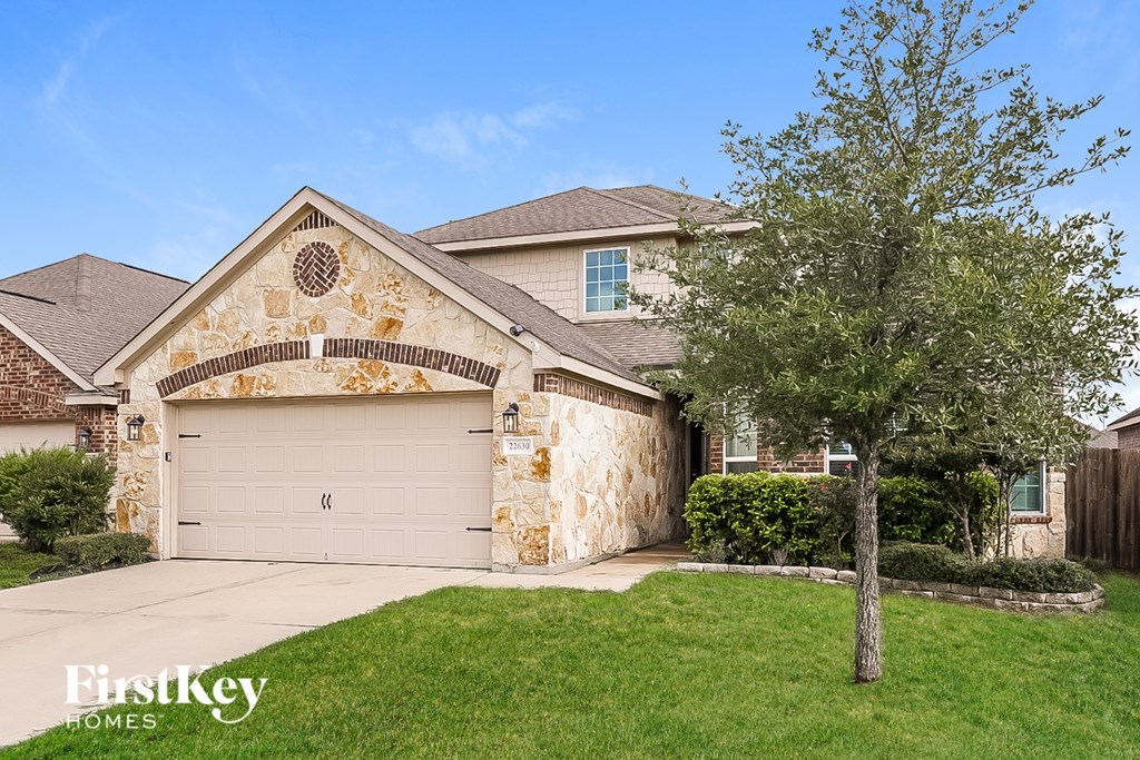 A house with a stone wall and a tree in front.