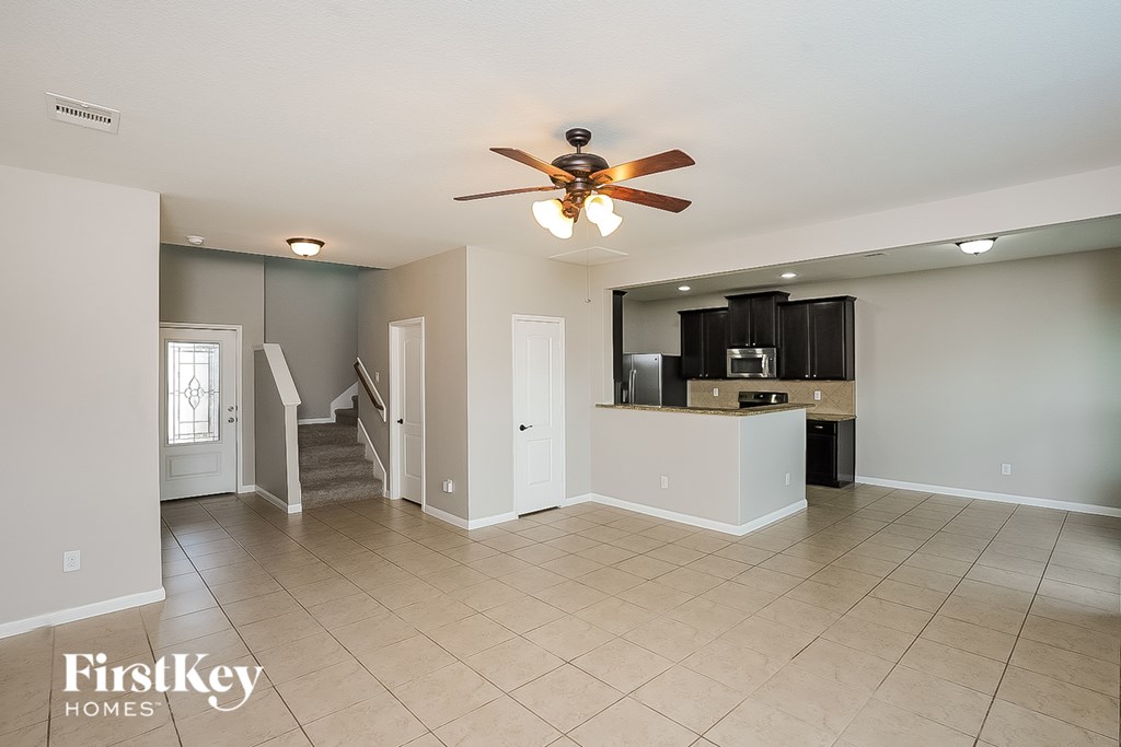 A spacious living room with a ceiling fan and tiled flooring.