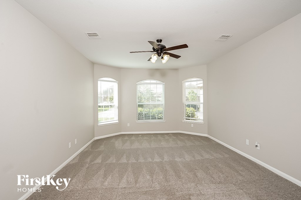 A spacious room with a carpeted floor and a ceiling fan.