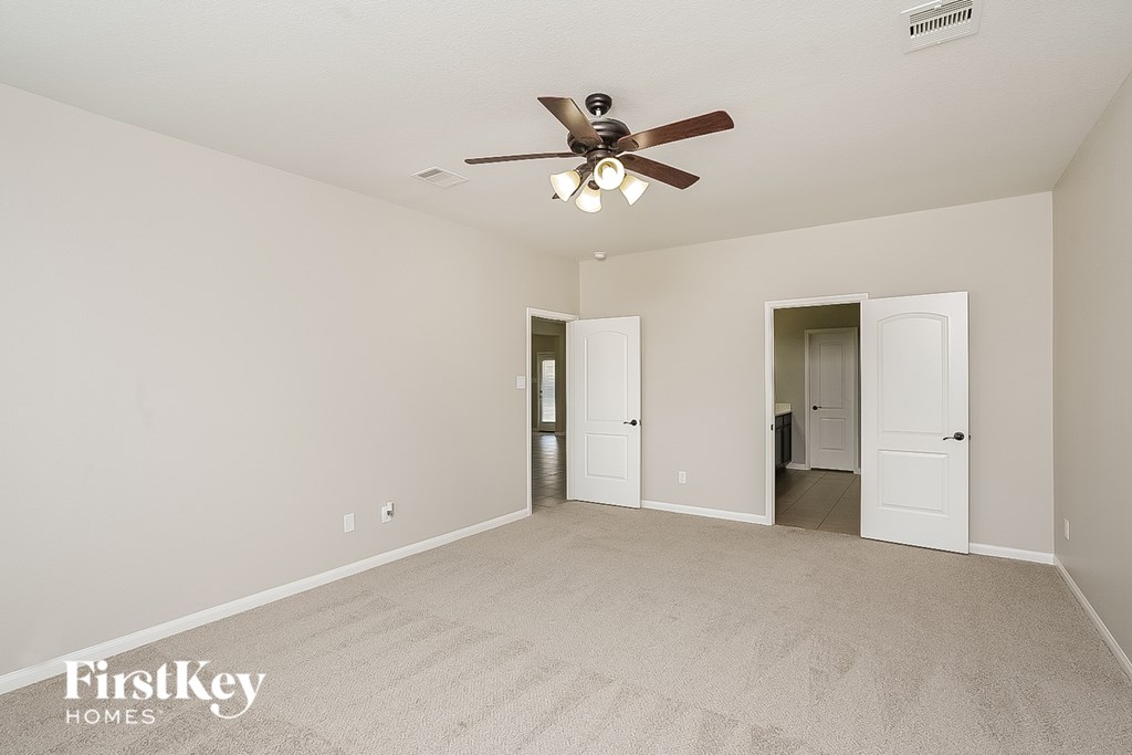 A spacious room with a ceiling fan and two doors.