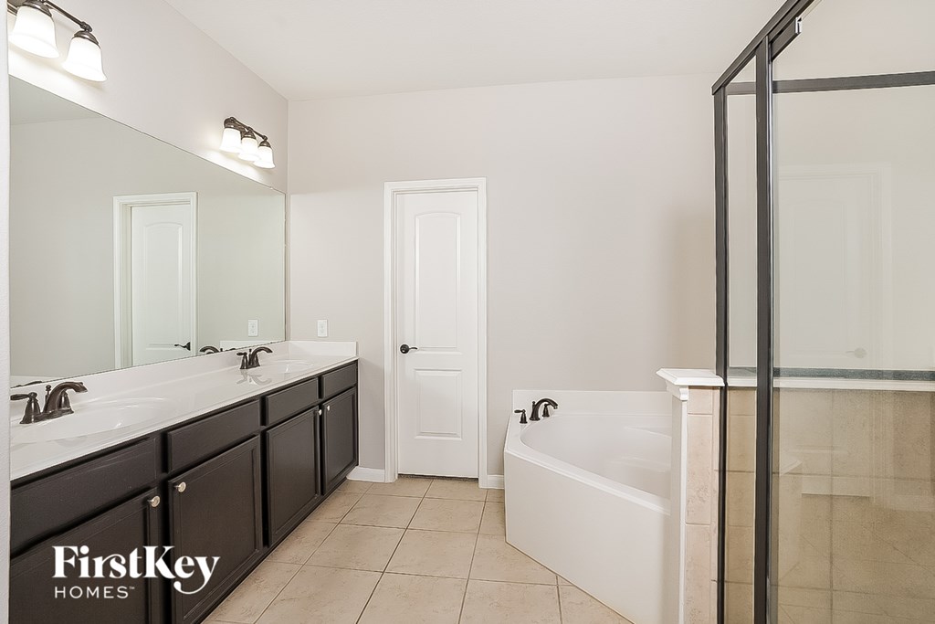 A bathroom with a white tub and a large mirror.