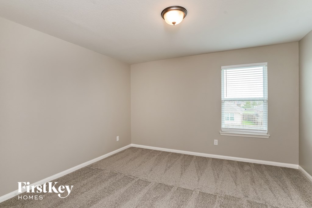 A room with a carpeted floor and a window with blinds.
