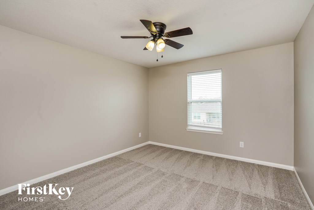 A room with a ceiling fan and carpeted floor.