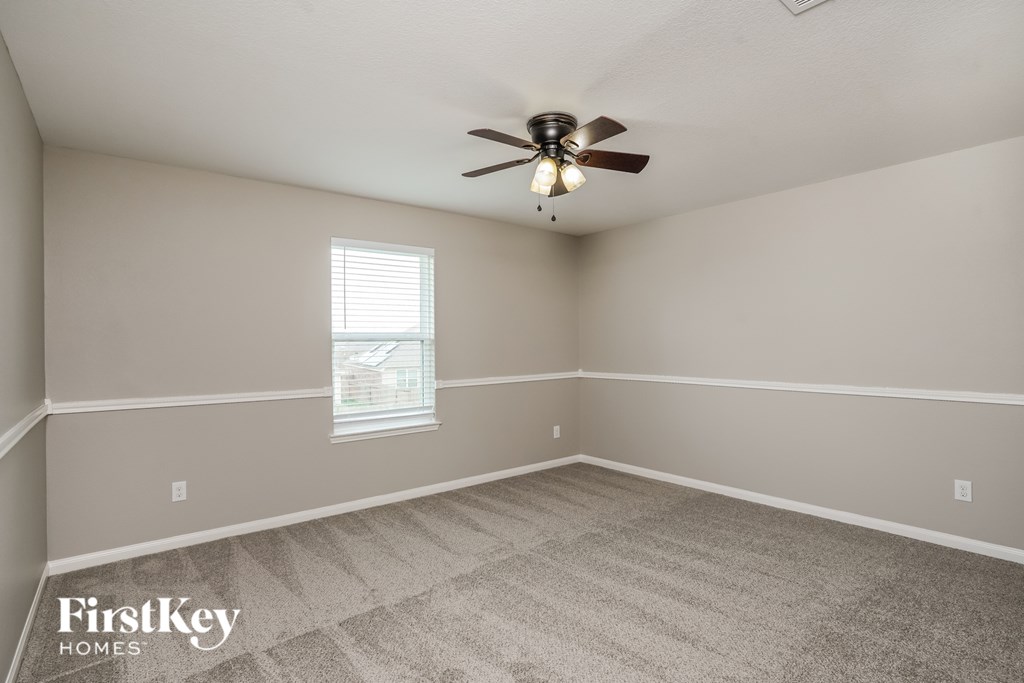 A room with a ceiling fan and a window with blinds.
