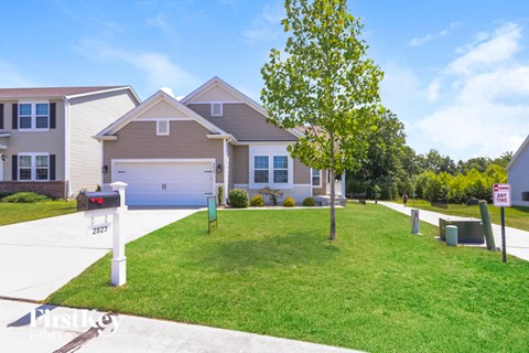 a house with a driveway and lawn in front of it