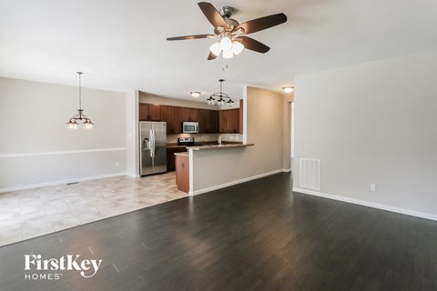 an empty living room and kitchen with a ceiling fan
