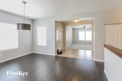 an empty living room and dining room with white walls and wood floors