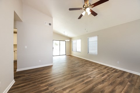 an empty living room with a ceiling fan
